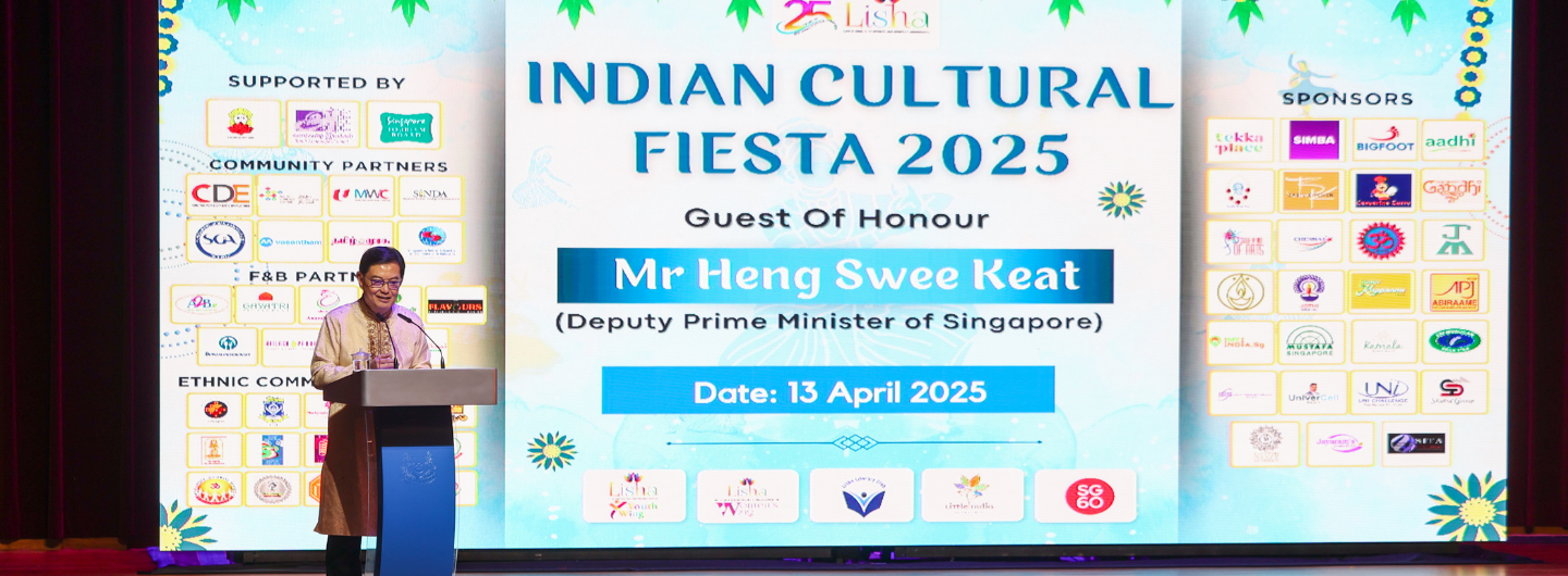 Man at podium with "Indian Cultural Fiesta 2025" backdrop listing sponsors, Lisha Youth Wing logo visible.